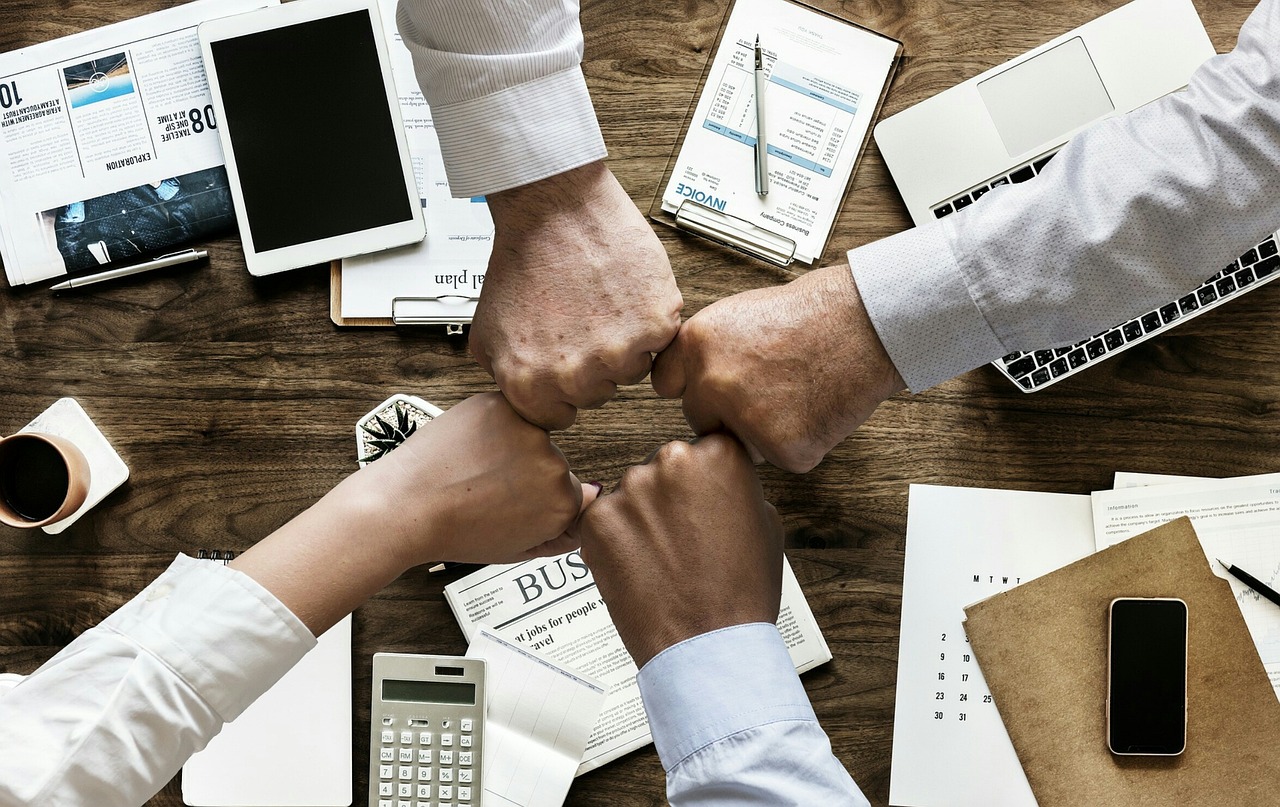 This is a group of people fist bumping after forming a business.